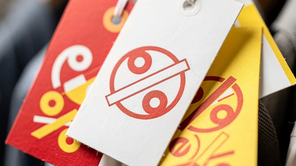 Macro view of sale tags showing different discount percentages with manufacturing dates visible in artistic blur