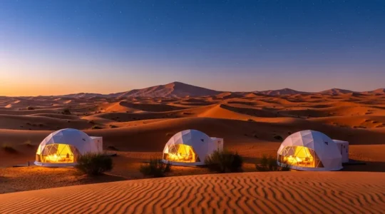 Luxury geodesic dome tents illuminated at twilight in UAE desert with starry sky