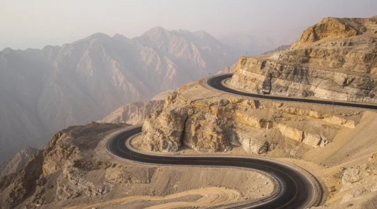 Winding mountain road ascending Jebel Jais with dramatic rocky peaks and hairpin curves