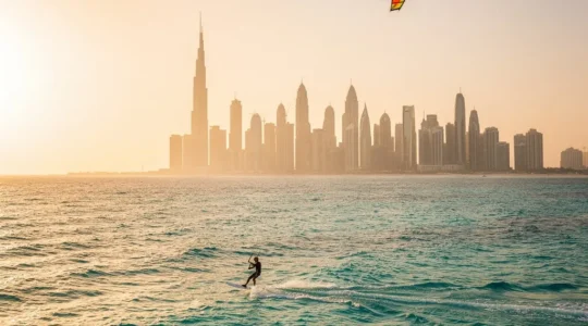 Kitesurfer riding waves with Dubai skyline during golden hour in winter season