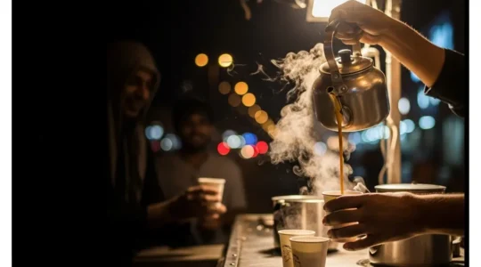 A roadside tea vendor in the UAE pours creamy karak chai into a plain paper cup under warm night lights, with soft negative space for a headline.